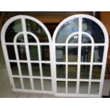 A pair of arch top wall mirrors in white frames