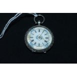 An Edwardian chased white metal pocket watch, key wound and open faced, the white enamel dial with