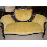 An Edwardian 2 seater settee in carved dark mahogany, with shield back, on cabriole legs in yellow