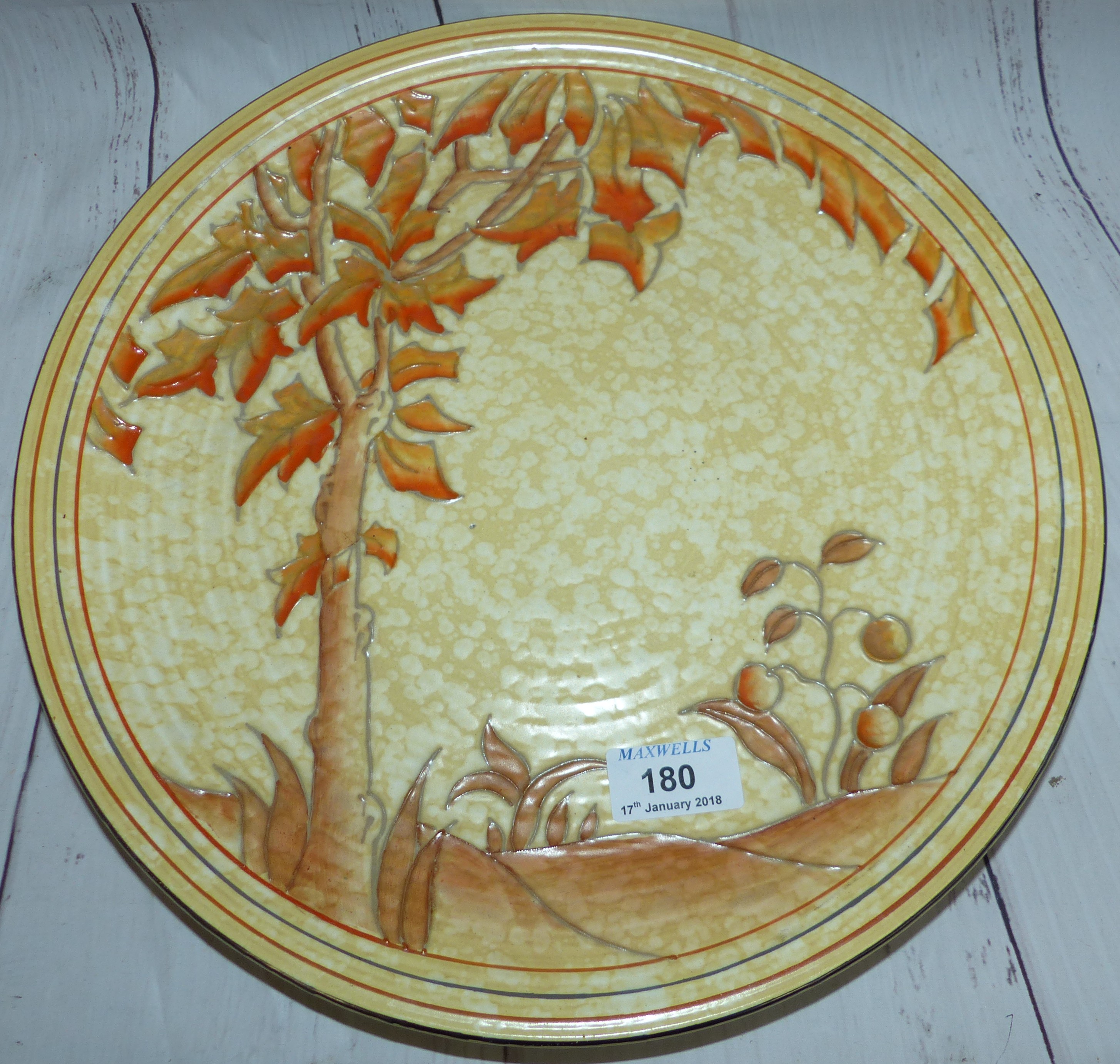 A Charlotte Rhead circular wall plaque decorated with a single tree in autumnal palette, signed 13"