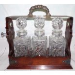 An Edwardian mahogany 3 bottle Tantalus with silver plated top and mounts