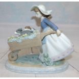 A Lladro group of a girl pushing puppies in a wheel barrow