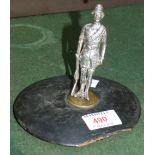 A silvered metal figure of a Boer war soldier mounted on a wooden tobacco jar lid 5" overall