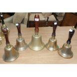 A large brass hand bell and 4 others