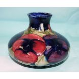 A William Moorcroft squat circular vase decorated with pansies against a blue ground, impressed