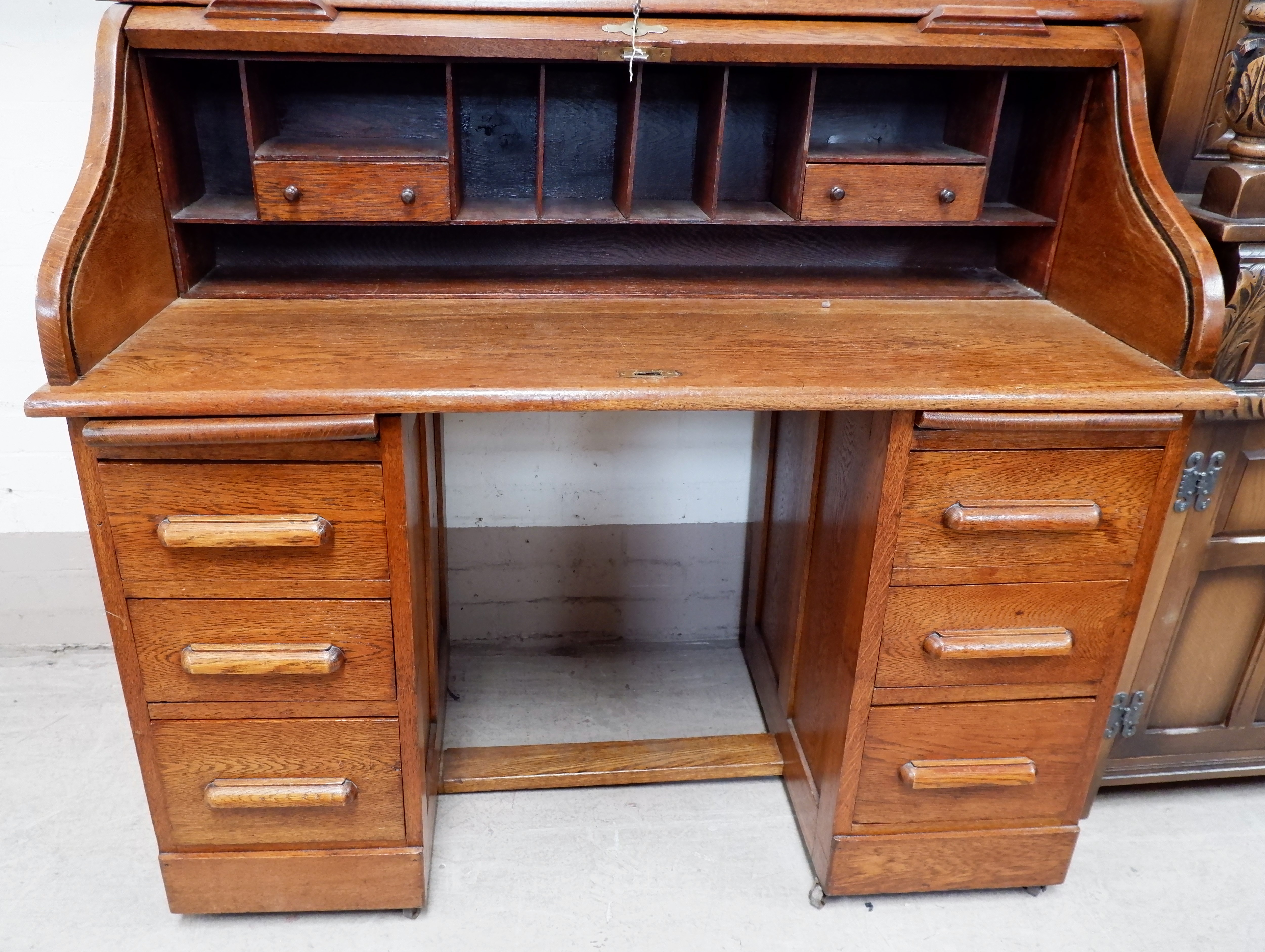 An early 20th century roll top desk with 'S' shaped scroll, part fitted interior and 6 drawers