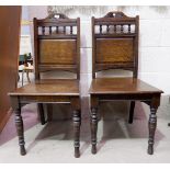 A pair of late Victorian oak panel back hall chairs