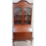 A 1920's mahogany quarter veneered bureau bookcase with dome top, 2 glazed doors, and 3 drawers,