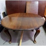 An early 20th century walnut oval wind out dining table on cabriole legs and castors, 1 spare