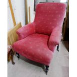 A Victorian armchair on turned ebonised legs and castors, reupholstered in red fabric