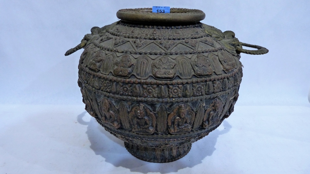 An Eastern brass vessel of archaic form with dragon mask handles and bands of embossed decoration.