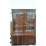 A mahogany library bookcase enclosed by a pair of glazed doors over base enclosed by a pair of panel