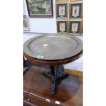 A wrought iron based occasional table with Benares type brass tray top