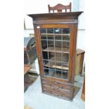 A 1930's oak bookcase enclosed by a leaded glazed door over two geometrically moulded base drawers