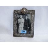 An early 20th century silver repousse decorated photograph frame. 8'' high. Losses and strut