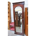 A mahogany wardrobe enclosed by door with arched plate