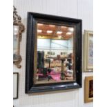 An ebonised wall mirror with gilt slip. 36'' high