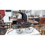 A miniature carriage with deep buttoned seat and fabric canopy on iron chassis with wood hafts.