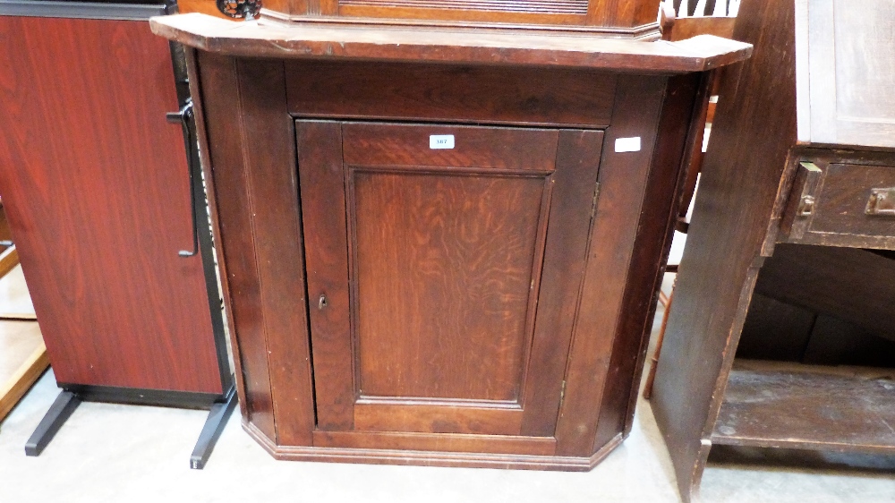 A George III oak hanging corner cupboard, the fielded door enclosing two shaped shelves