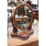 A Victorian mahogany dressing glass with oval plate and trinket well to base