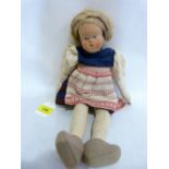 An early 20th century continental Dutch girl doll with carved wood head and fabric body and limbs.