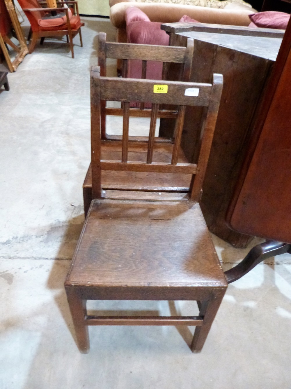 A pair of early 19th century joined oak country chairs with stave backs and plank seats on square