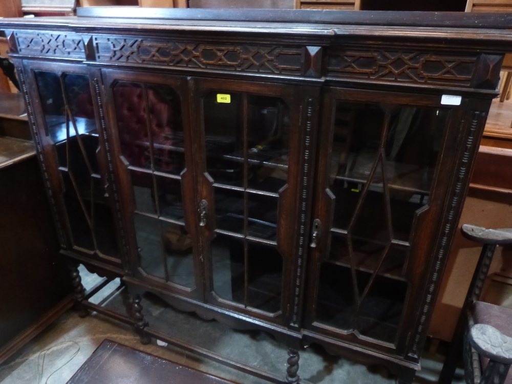 A 1930s oak bookcase enclosed by four astragal glazed doors on barleytwist supports. 60' wide