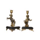 PAIR OF LATE VICTORIAN GILDED CAST METAL FIGURAL CANDLESTICKS each modelled as putti holding a rope,