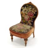 A VICTORIAN WALNUT NURSING CHAIR, IN CONTEMPORARY FLORAL WOOLWORK, ON POTTERY CASTORS, AN