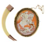 A GOLD MOUNTED BOAR'S TUSK PENDANT AND A 19TH C CAMEO BROOCH, THE OVAL SHELL CARVED WITH ST.