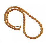 A NECKLACE OF SIXTY AMBER BEADS 15.3g