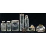 FIVE VARIOUS SILVER CAPPED GLASS JARS OR BOTTLES, TWO BRASS MOUNTED INKWELLS AND ANOTHER ITEM