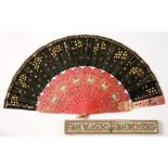 A CHINESE CARVED AND RED STAINED, INLAID AND GILT BONE FAN, WITH SEQUIN DECORATED BLACK SILK LEAF,