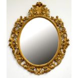 A VICTORIAN CARVED GILTWOOD AND COMPOSITION OVAL MIRROR, THE BEVELLED PLATE WITH SCROLLING