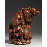 A CHINESE CARVED BAMBOO FIGURE OF SHOU-LAO on a rock, holding a peach bough in his left hand and