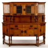 AN ARTS AND CRAFTS SPLAY FRONTED OAK SIDEBOARD, C1900, THE SHELVED SUPERSTRUCTURE WITH WAVY SLATS