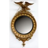 A REGENCY STYLE GILTWOOD MIRROR, THE CONVEX PLATE IN CIRCULAR FRAME CRESTED BY AN EAGLE ON ROCKS,