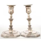 A PAIR OF EDWARD VII SILVER CANDLESTICKS, THE SQUARE PILLAR ON DISHED OCTAGONAL FOOT, NOZZLES