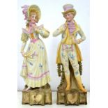 A PAIR OF CONTINENTAL PAINTED BISCUIT FIGURES OF AN ELEGANT YOUNG WOMAN AND HER SUITOR, 38CM H,