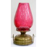 A BRASS OIL LAMP WITH WIRE HANDLES AND TRELLIS MOULDED CRANBERRY GLASS TAPERED SHADE, 48CM H, 20TH