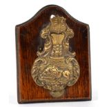 A VICTORIAN EMBOSSED BRASS LETTER CLIP, ON OAK BOARD, 11CM H