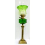 AN EDWARDIAN BRASS COLUMNAR OIL LAMP WITH EMERALD GREEN GLASS FOUNT AND BRASS BURNER, GREEN SHADED