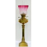 AN EDWARDIAN BRASS OIL LAMP, THE SQUARE PILLAR ON STEPPED FOOT WITH BRASS FOUNT, BURNER AND