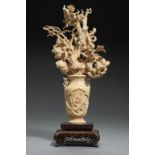A CHINESE IVORY CARVING OF A VASE OF FLOWERS, C1900 26cm h, on later affixed hardwood base++Very