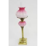 A VICTORIAN BRASS CORINTHIAN COLUMN OIL LAMP WITH PINK SHADED GLASS FOUNT, BRASS BURNER AND MATCHING