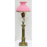 AN EDWARDIAN BRASS CORINTHIAN COLUMN OIL LAMP, WITH FACETED GLASS FOUNT AND BRASS BURNER, PINK