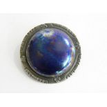 AN ARTS AND CRAFTS SILVER BROOCH SET WITH A CONTEMPORARY IRIDESCENT GLAZED RUSKIN POTTERY ROUNDEL,