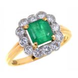 AN EMERALD AND DIAMOND CLUSTER RING with central step cut emerald (6.1 x 6.4mm) gold hoop, London