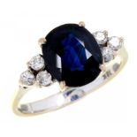 A SAPPHIRE AND DIAMOND RING the larger cushion shaped sapphire between triple diamond shoulders,