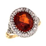 AN ANTIQUE HESSONITE GARNET AND DIAMOND CLUSTER RING with diamond shoulders, spirally fluted gold